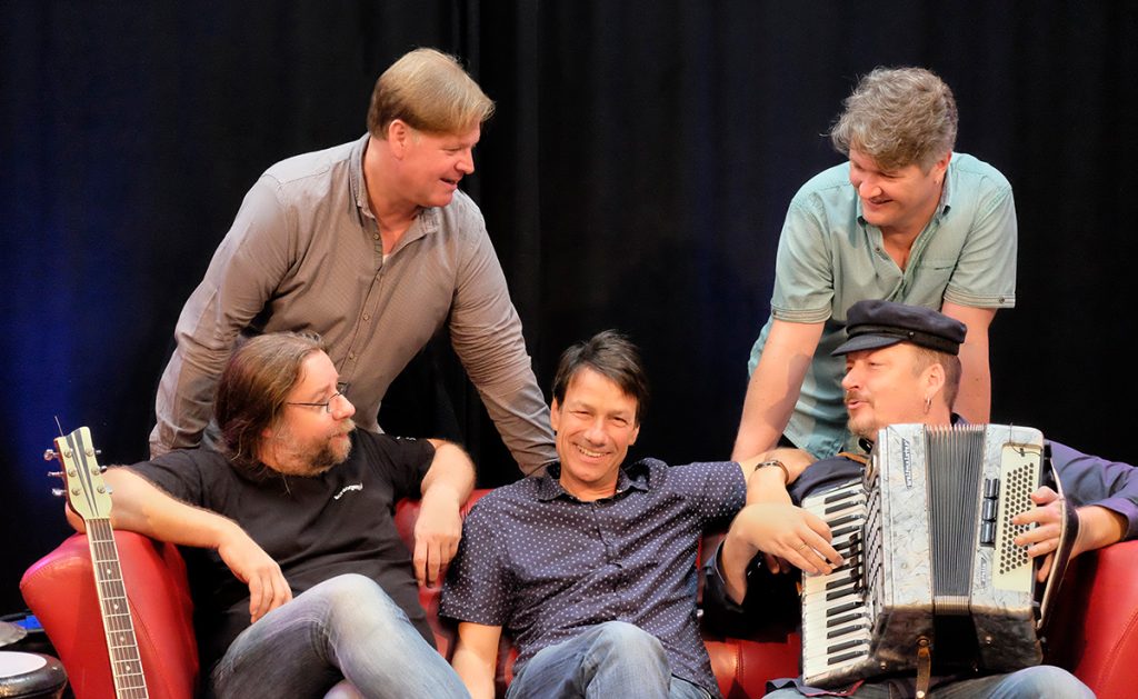 Foto: die Bandmitglieder von Goldstück auf einem roten Sofa