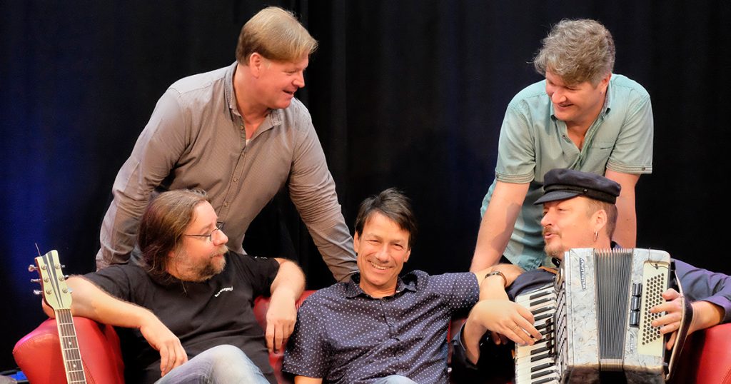 Foto: die Bandmitglieder von Goldstück auf einem roten Sofa