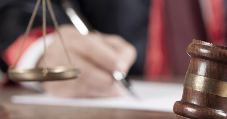 Foto: Hand unterzeichnet, davor Waage, unscharf